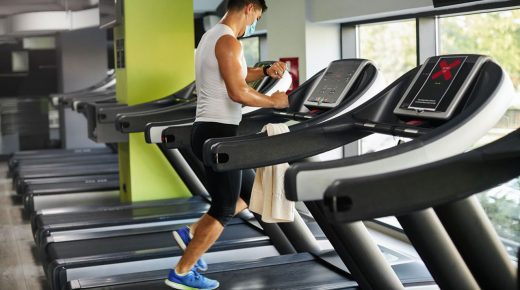 Young man exercising in gym with protective face masks after coronavirus pandemic.